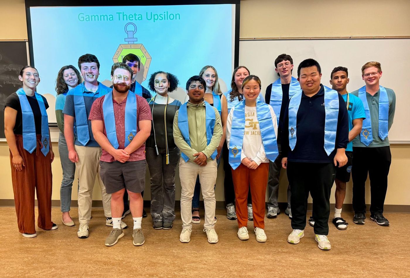 Gamma Theta Upsilon induction ceremony at Binghamton University, with inductees wearing the honor society's stoles